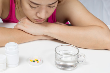 asian beautiful woman with tablets, medicine, water suffering insomnia, fever and headache