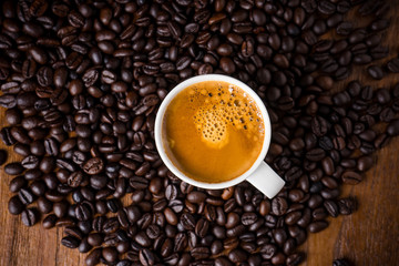 Coffee cup and coffee beans on wooden background. Top view.