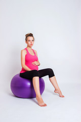 Fototapeta na wymiar pregnant woman practicing yoga on a light background