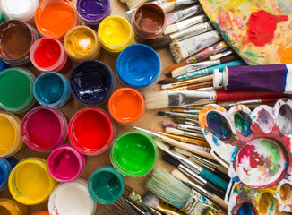 Colorful paints, brushes, palette on the wooden background. The workplace of the artist. Banner for the school.