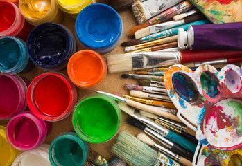 Colorful paints, brushes, palette on the wooden background. The workplace of the artist. Banner for the school.