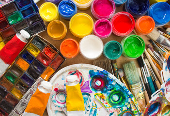 Colorful paints, brushes, palette on the wooden background. The workplace of the artist. Banner for the school.
