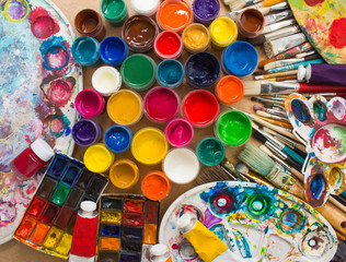 Colorful paints, brushes, palette on the wooden background. The workplace of the artist. Banner for the school.