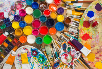 Colorful paints, brushes, palette on the wooden background. The workplace of the artist. Banner for the school.