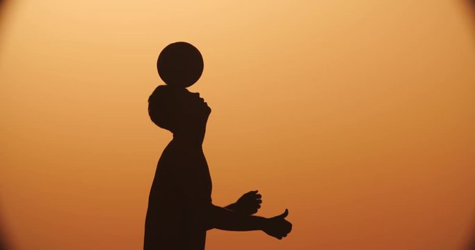 football player silhouette , practicing with the ball,the sunset Golden hour,heading slow motion