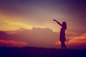 silhouette young woman pointing forward to Dream ahead in sunset