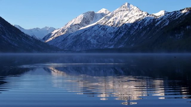 Circles on the water of Lower Multinskoe lake in the Altai Mountains  on blue sky background.