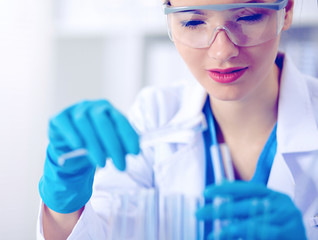 Woman researcher is surrounded by medical vials and flasks, isolated on white background