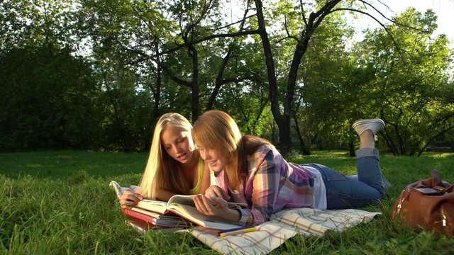 Happy Teenage girls reading a book outdoors.