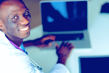 Young african doctor working on laptop at desk