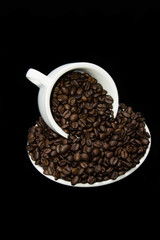 Mug of coffee beans with saucer on black background.