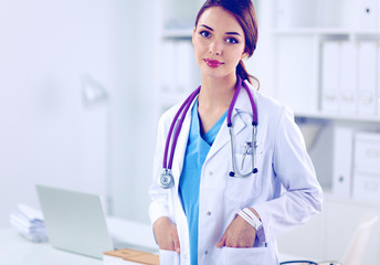 Portrait of young woman doctor with white coat standing in hospital