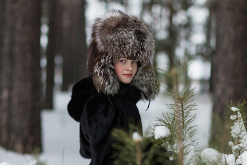 Girl in a fur hat winter frosty day walking in the woods