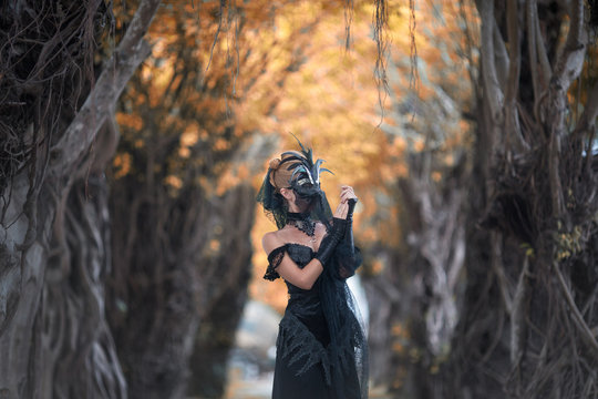 Woman in mysterious place,creative mask and long black dress create dramatic atmosphere