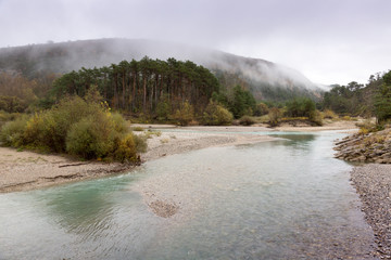 Fog climbs down mountains to the river