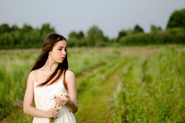 girl walking in a field with a flower