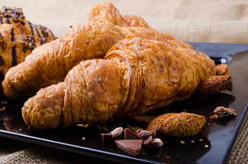 Closeup Croissants on a wooden plate. chocolate and almonds. Foc