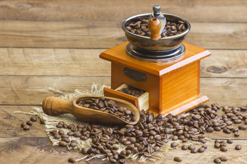 coffee grinder on wooden background with roasted coffee beans