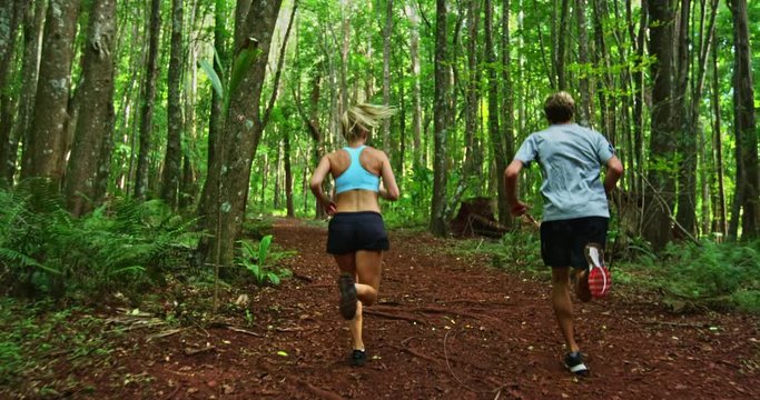 Athletic couple running together in the forest