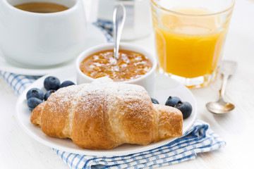 fresh croissant with orange jam, blueberries and coffee
