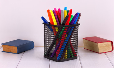 Fototapeta premium Multicolored markers in the stand next to small books