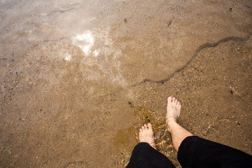 Man's feet on the sand in the river
