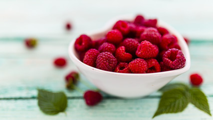 Fresh raspberries in bowl on wooden background.