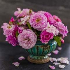 Beautiful pink roses in an old vase. Still life on dark background.