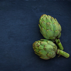 Obraz premium Organic fresh artichokes on black grunge moody table