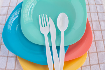 colorful fork ,knife and spoon put on colorful plastic plate at tablecloth