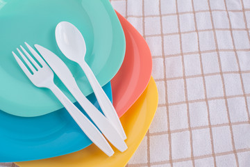 colorful fork ,knife and spoon put on colorful plastic plate at tablecloth