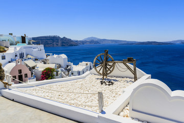 Oia village on Santorini island in Greece. View with white houses and roofs in background blue sea.