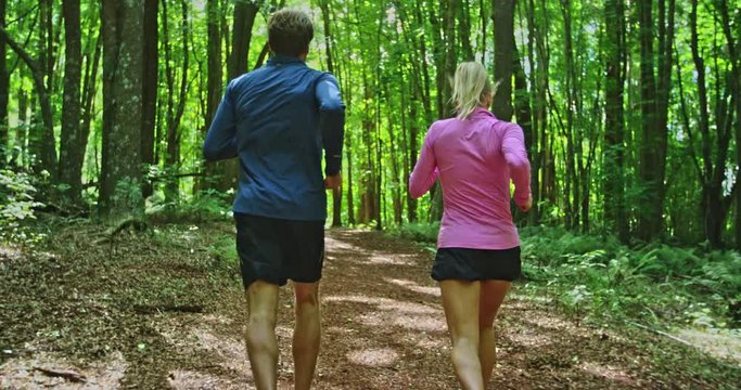 Athletic couple running together in the forest