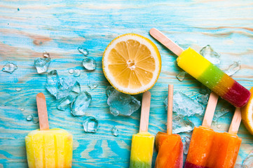 Colorful ice lolly and friuts on blue wooden background