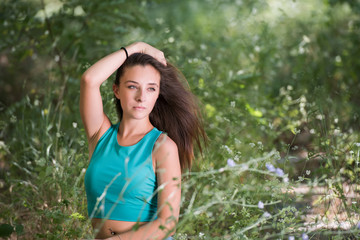 Naklejka na ściany i meble Cute girl with straight hair wear blue top shirt and jean sitting among green grass