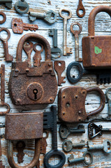Old rusty keys and padlocks on white wooden table