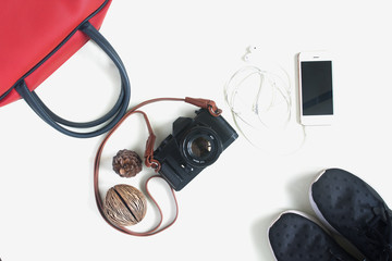 Flat lay of travel items with film camera, smartphone, red hand