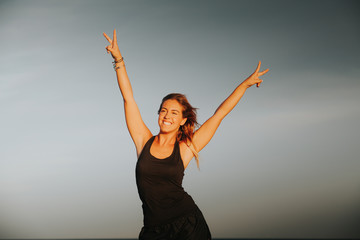Blonde fitness woman raising arms and doing victory sign with the hands. Success concept.
