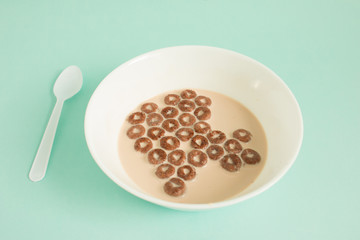 Close up of chocolate cereal with milk on blue background.