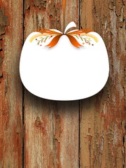 Close-up of one blank pumpkin shaped frame hanged by brown ribbon on scratched wooden background
