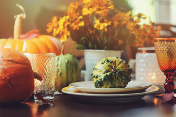 autumn traditional table setting for Thanksgiving or Halloween, with candles, flowers and pumpkins.