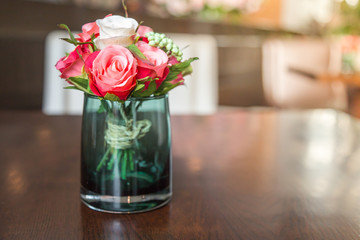 Fake roses arranged in a glass on the table.
