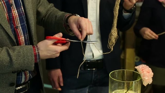 Men's hands cutting the rope with scissors.