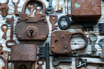 Old rusty keys and padlocks on white wooden table
