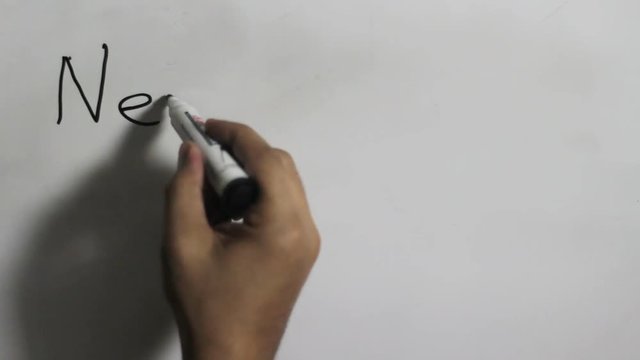 Hand writing a "Never Stop Dreaming" message on a white board using a black marker
