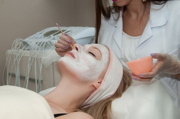 Hardware cosmetology. Lovely young woman with cream mask in a beauty parlour.