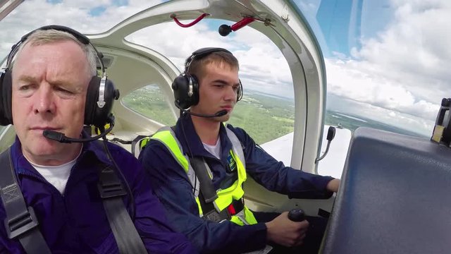 Time lapse with cockpit view of young student pilot aviating aircraft with help of middle aged flight instructor 