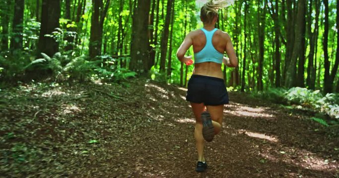Athletic young woman running in the forest