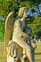 Fototapeta na wymiar Engelsfigur aus Stein auf einer Wiese am Friedhof