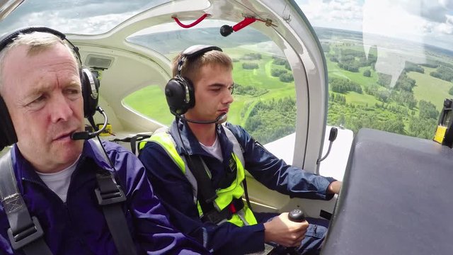 Action camera shot from cockpit of airplane of novice pilot practicing in air as middle aged flight instructor mentoring him 